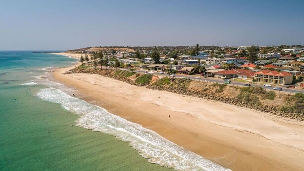 Un pueblo costero con una playa arenosa, casas a lo largo de la costa y una vista despejada del océano.