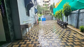 A narrow alleyway with patterned pavement, a metal sink, and blue trash bins. - Astha Home Shared Pool Rooms (Mumbai)