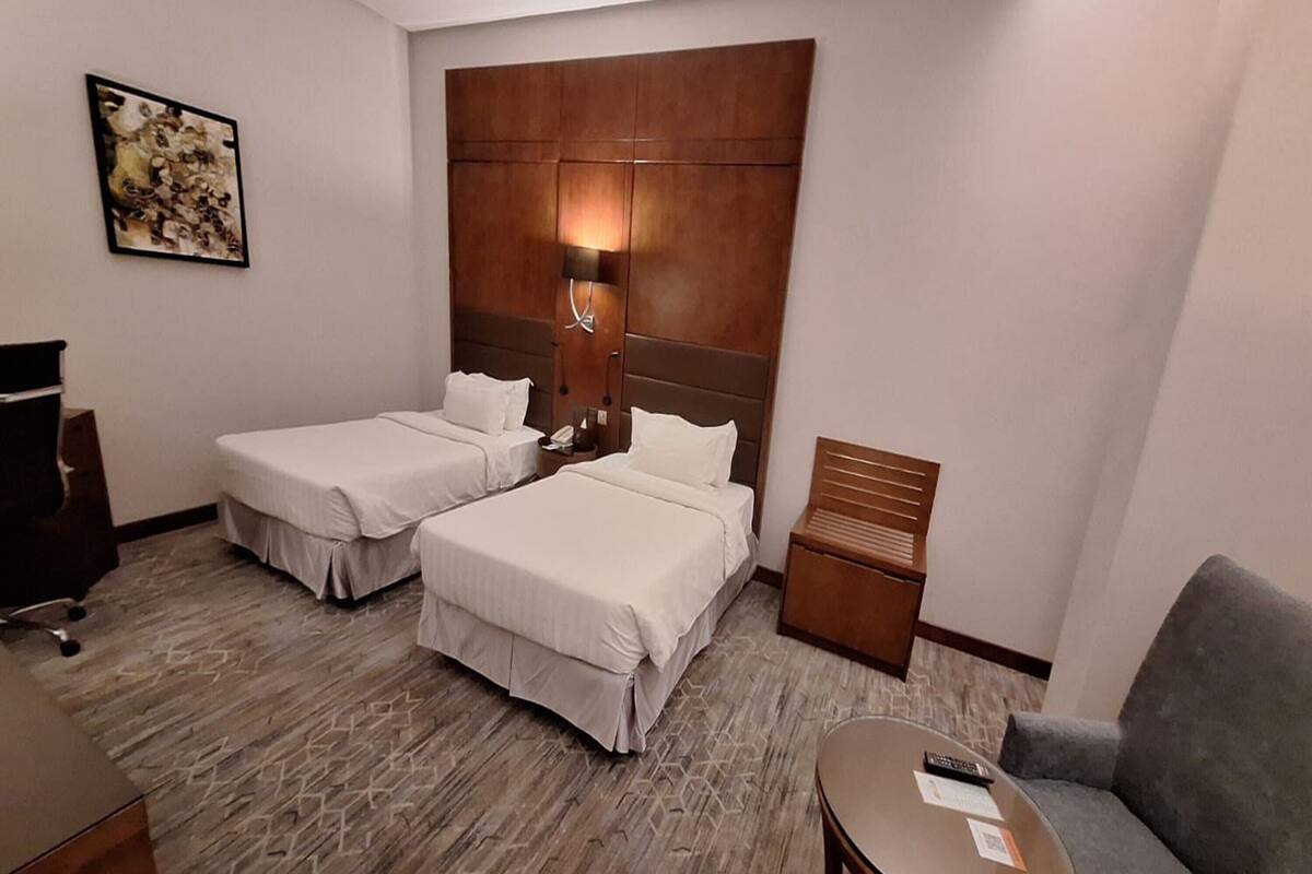 Habitació d'hotel amb dos llits, una taula de treball, una cadira i una taula petita.