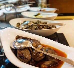 A dining table with various dishes, including a bowl of mushrooms in sauce and another with a different type of food. - Sunday Qaser Al Hamra (Riyadh)