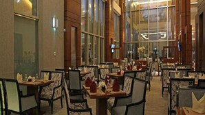 Uma ampla área de jantar com várias mesas e cadeiras, grandes janelas e um design de interiores moderno.