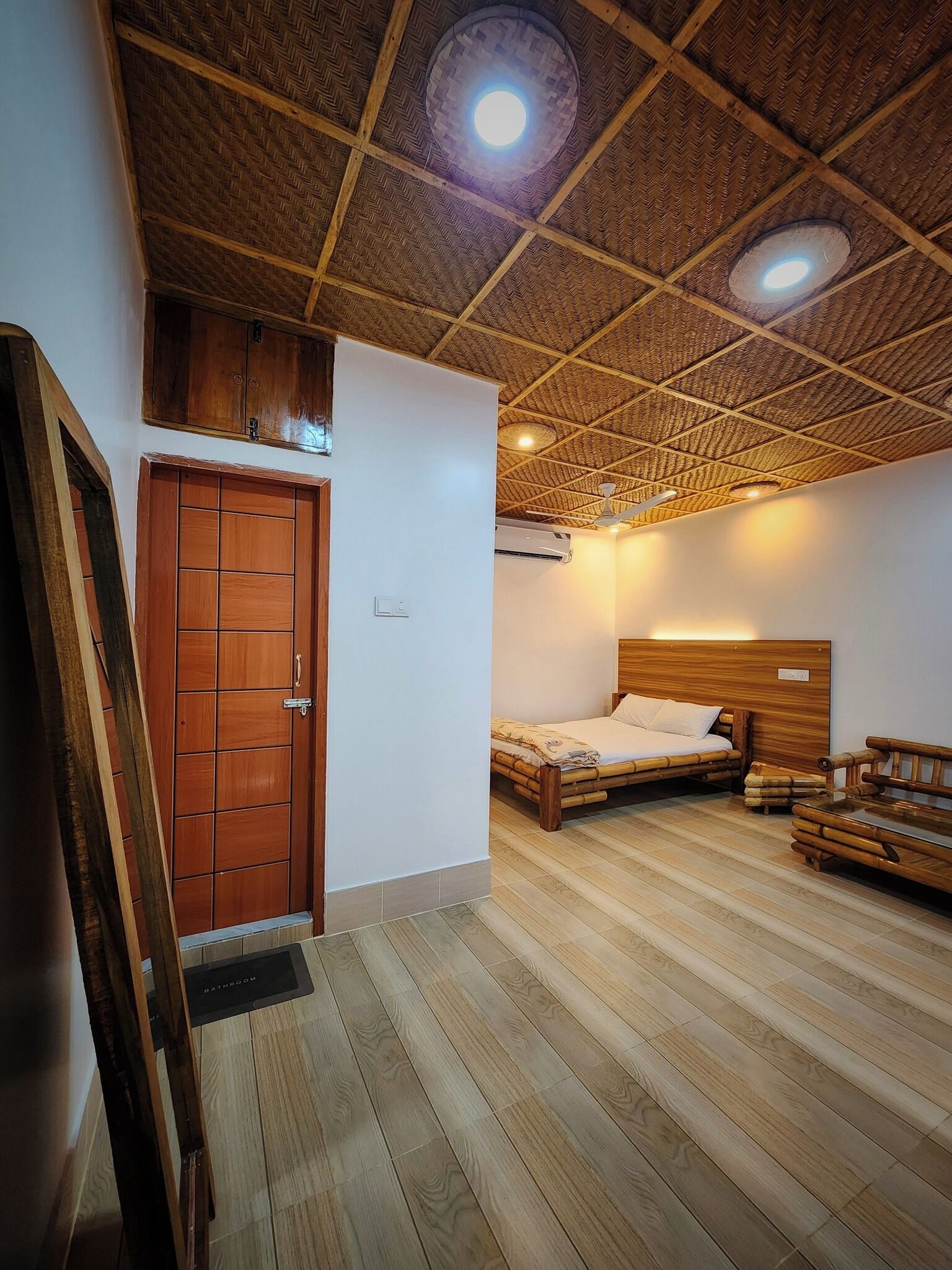 Una habitación con piso de madera, una cama con cabecera de madera, un armario de madera y un techo con diseño tejido.