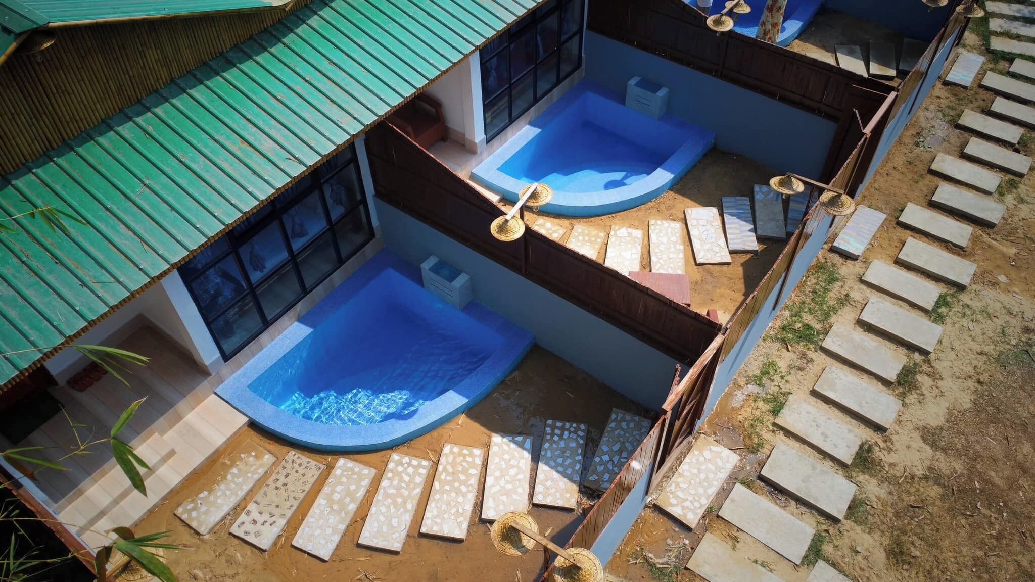 Un edificio de dos plantas con piscina en la planta baja y un balcón con vistas a la piscina.