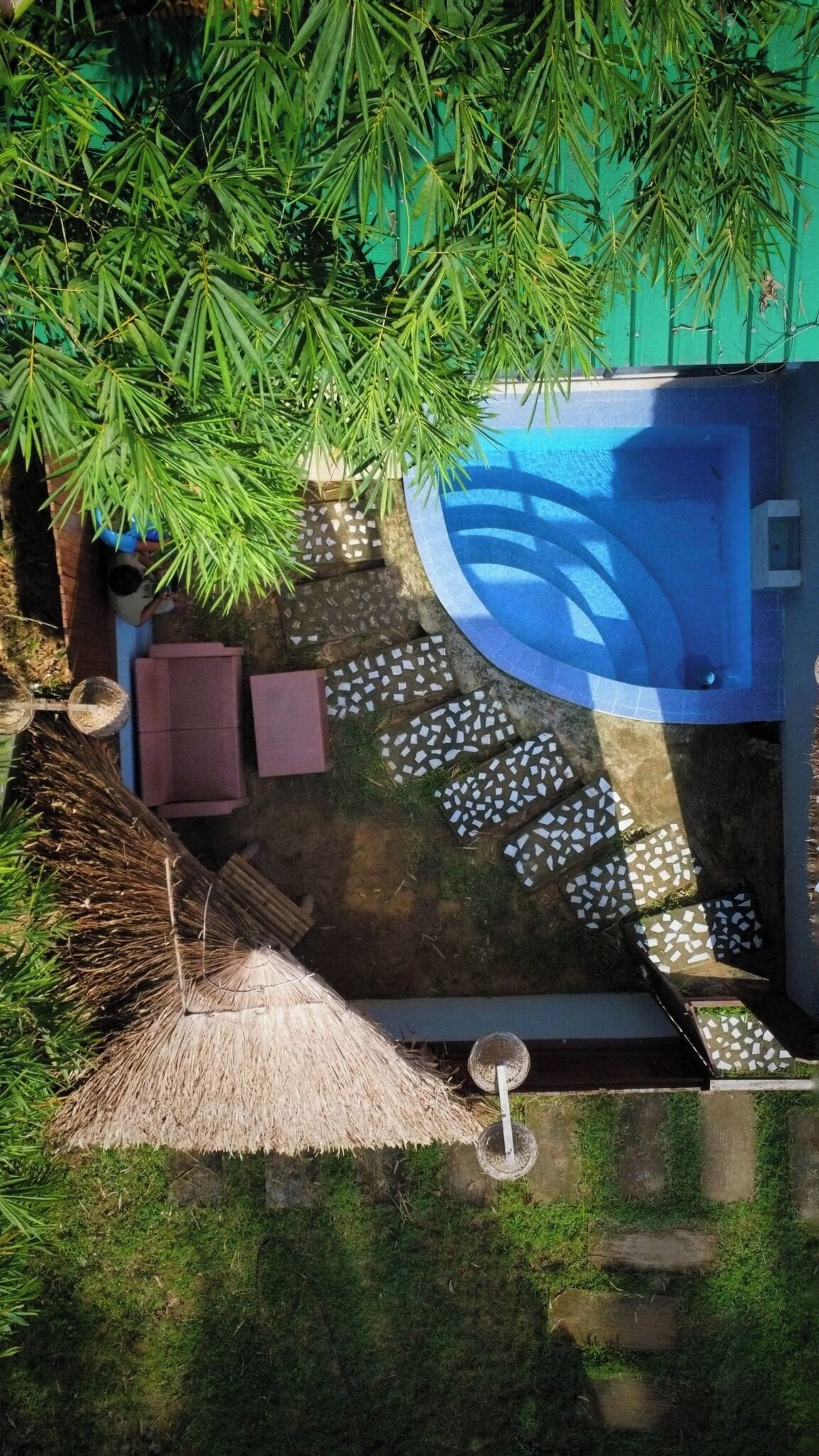 Una piscina exterior con techo de paja y baldosas de piedra.