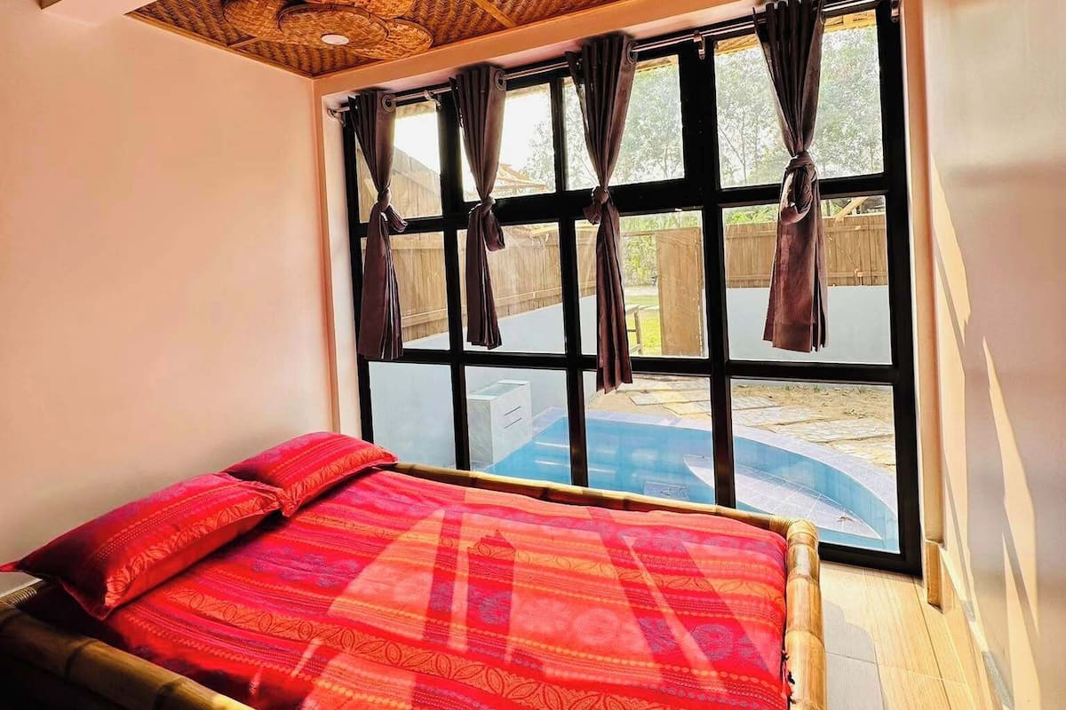 Een kamer met een bed, grote ramen en een plafond met geweven patronen.