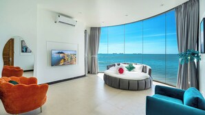 Un salon moderne doté d’une grande fenêtre incurvée qui offre une vue sur la mer.
