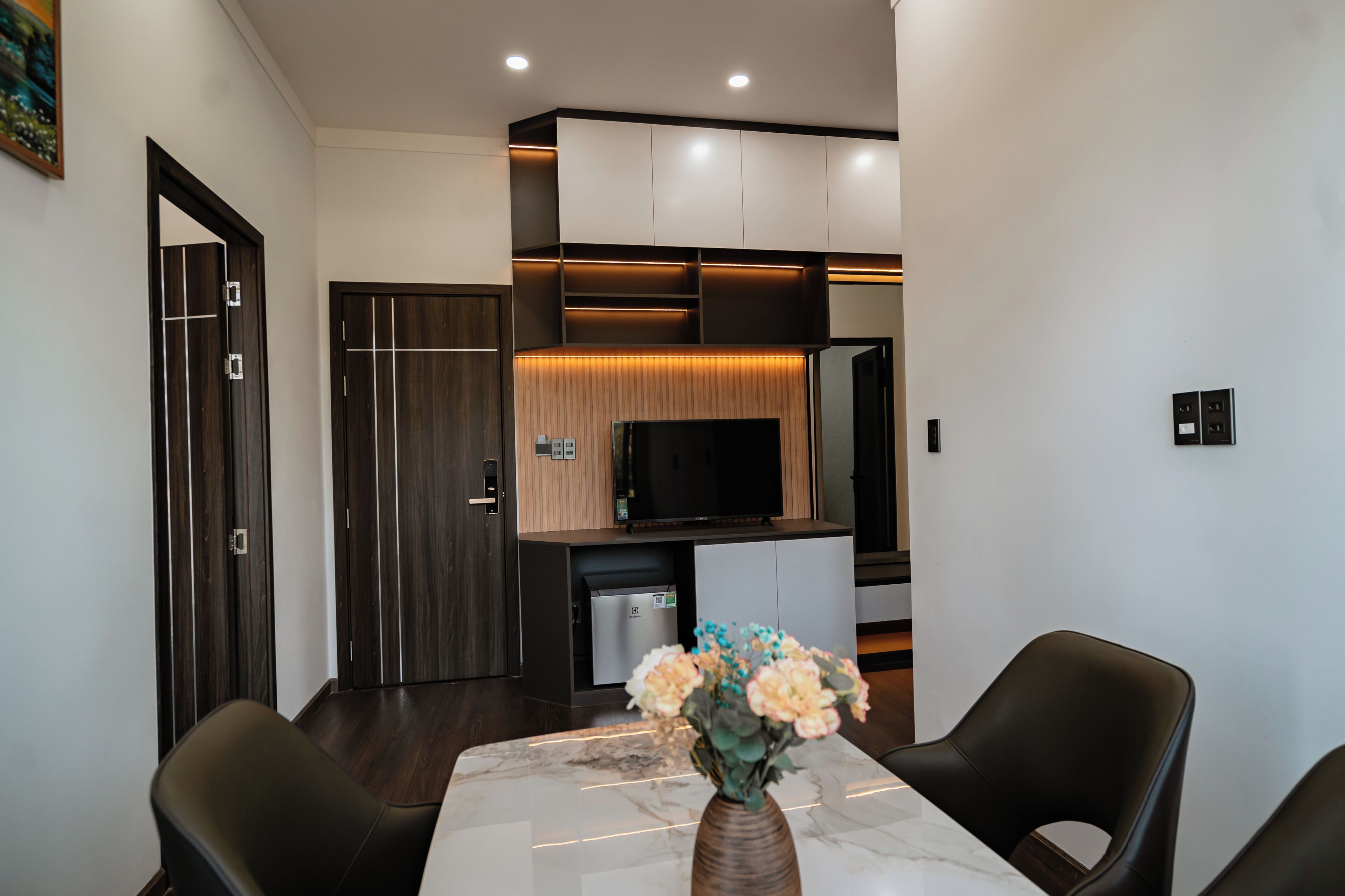 A modern dining area with a marble table, black chairs, and a vase with flowers.