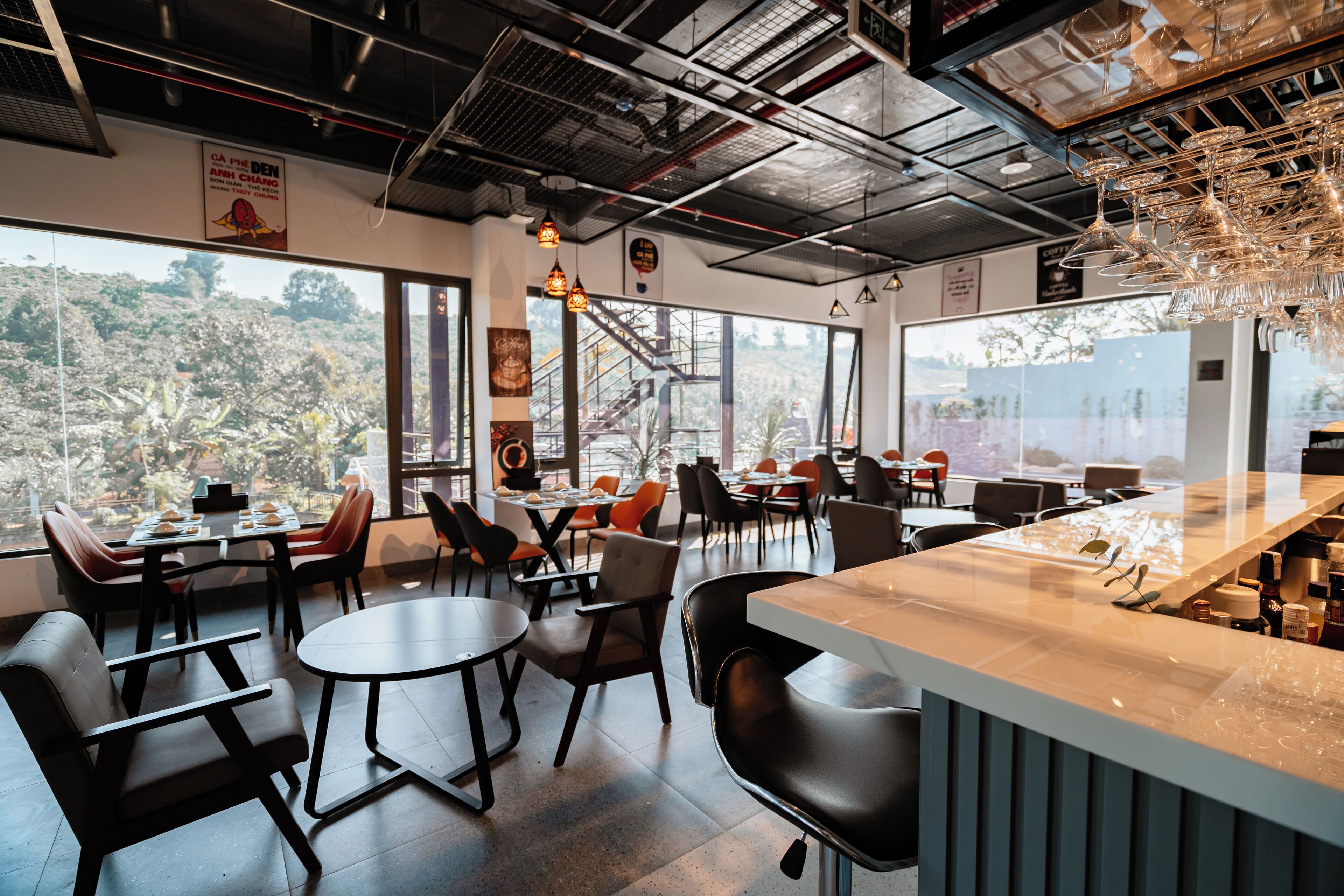 Un restaurante moderno con barra, amplios ventanales que ofrecen vistas al exterior y una variedad de opciones de asientos.