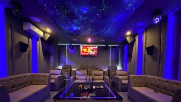 A home theater with a starry ceiling, comfortable seating, and a central coffee table with blue LED lights.