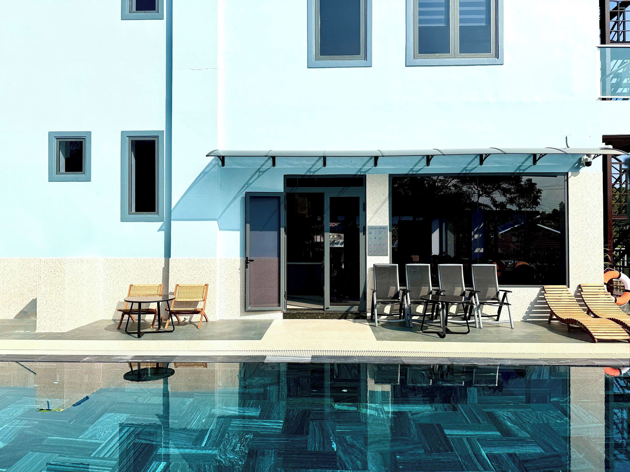 Ein modernes Gebäude mit Pool, Sitzgelegenheiten im Freien und einem überdachten Eingang.