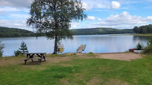 A lakeside picnic area with a bench, a picnic table, and a boat. - 7 Person Holiday Home in Kil (Kil)
