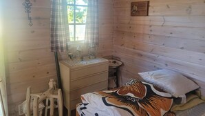 A wooden cabin room with a bed, a small table, a chair, and a window with curtains. - 7 Person Holiday Home in Kil (Kil)