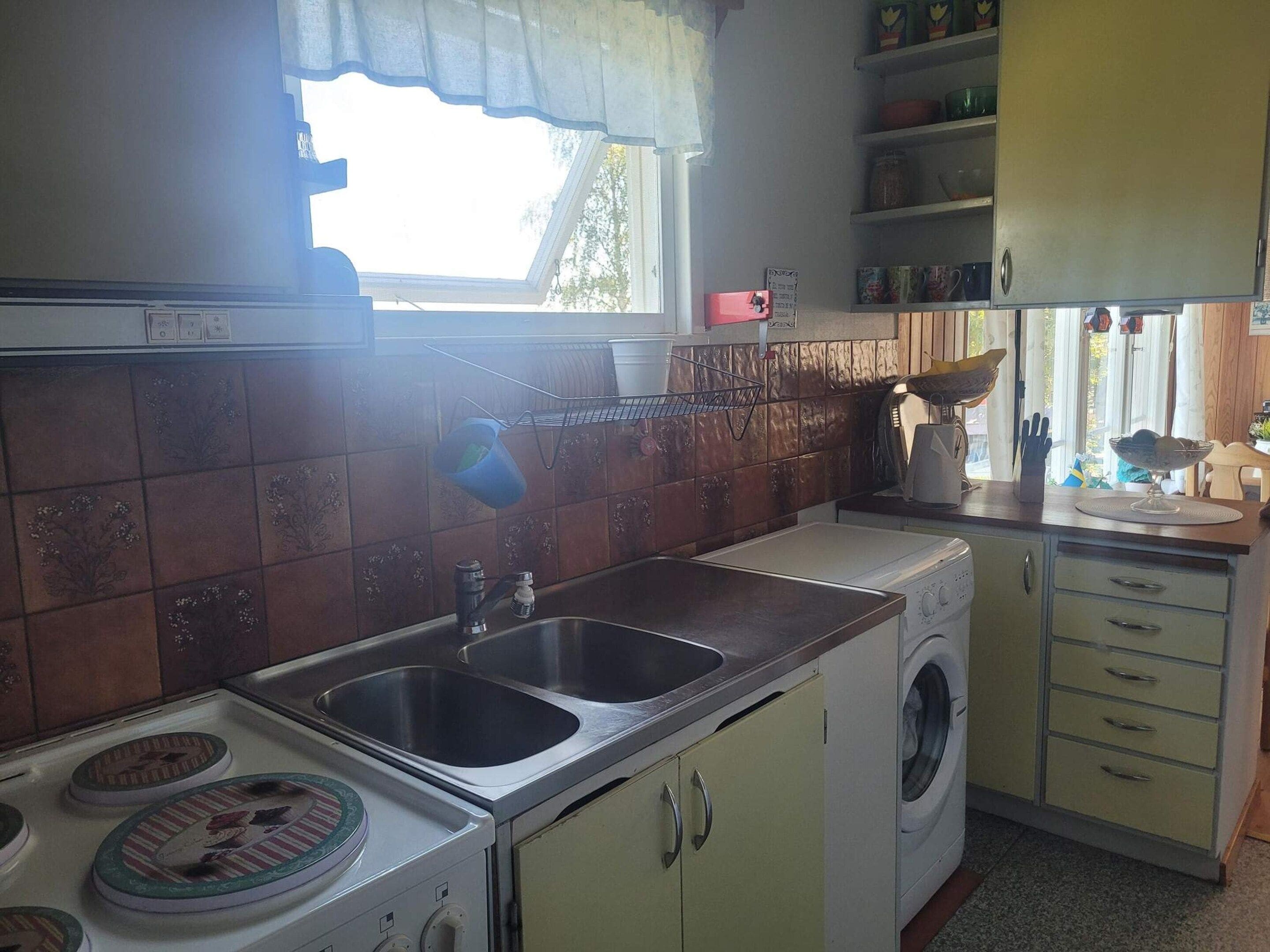 A kitchen with a sink, stove, and washing machine.