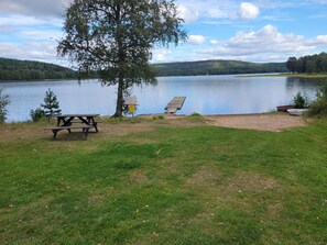 A lakeside picnic area with a bench, a picnic table, and a boat. - 7 Person Holiday Home in Kil (Kil)