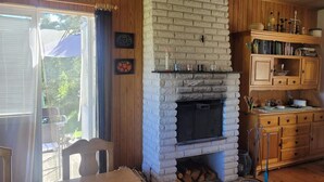 A cozy room with a stone fireplace, wooden cabinets, and a dining area with a table and chairs. - 7 Person Holiday Home in Kil (Kil)
