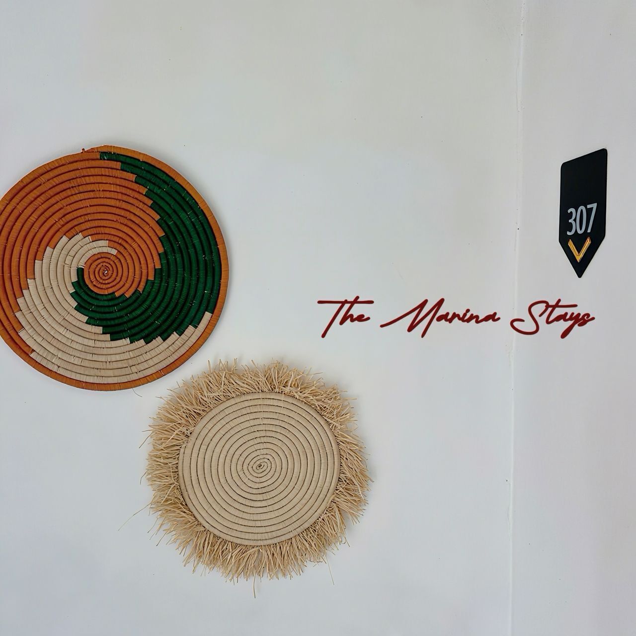 Two circular wall decorations with concentric patterns, a black sign with the number '307', and the text 'The Marina Stay' in cursive.