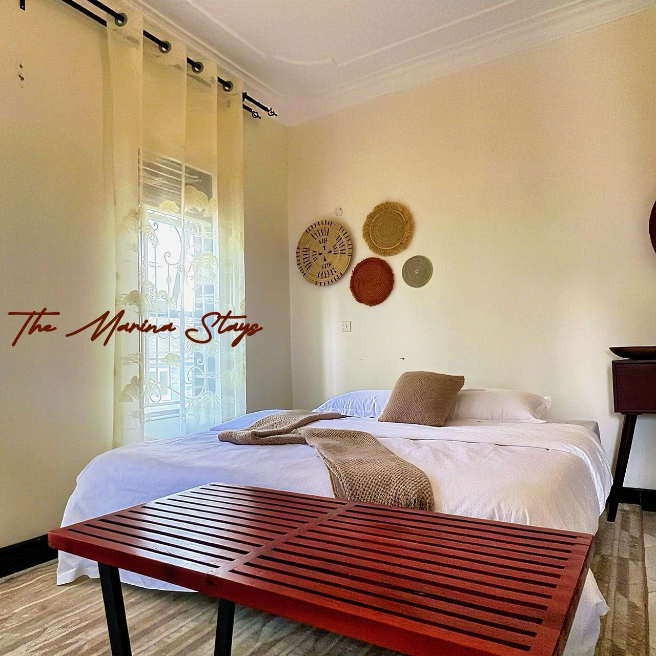 A bedroom with a bed, a wooden table, and a window with curtains.