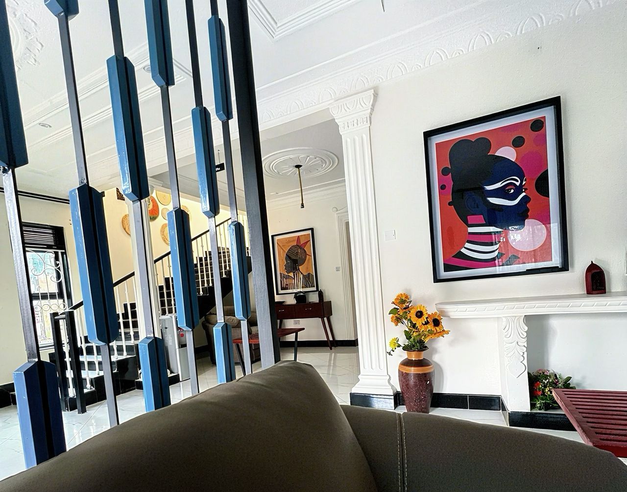 A modern interior with a black sofa, a white fireplace, and a framed abstract painting.