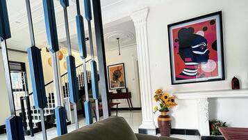 A modern interior with a black sofa, a white fireplace, and a framed abstract painting.
