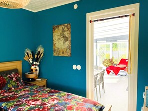 A bedroom with a bed, a map on the wall, and a view of an outdoor area with a red chair. - 4 Star Holiday Home in Tvarred (Tvärred)