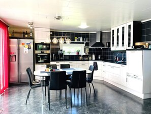 Una cocina moderna con comedor, que incluye refrigerador, horno y salpicadero de azulejos negros.