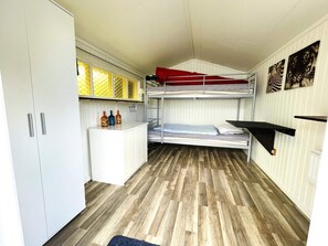 Ein kleines Zimmer mit Etagenbetten, einer kleinen Küchenzeile und Holzboden.