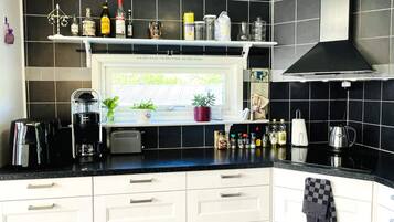 A kitchen with white cabinets, a black countertop, and various kitchen appliances.