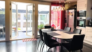 Une cuisine moderne avec un coin repas, comprenant une grande table, des chaises et un réfrigérateur.