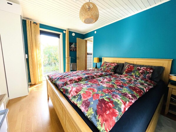 Un dormitorio con cama, cabecero de madera y vistas al exterior.