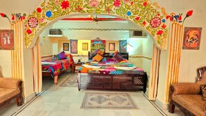 A room with a bed, two sofas, and an ornate archway with floral designs. - Jodhpur Heritage Haveli (Jodhpur)