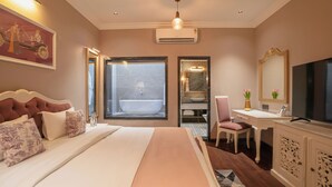 A well-appointed hotel room with a large bed, a desk, a television, and a bathroom with a bathtub. - Chandralok - A Boutique Hotel in Udaipur Near Fateh Sagar Lake (Udaipur)