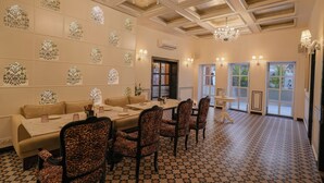 A dining area with a long table, patterned chairs, and decorative wall panels. - Chandralok - A Boutique Hotel in Udaipur Near Fateh Sagar Lake (Udaipur)
