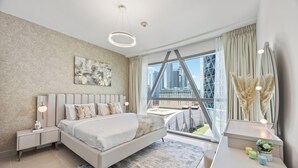 Une chambre moderne avec un grand lit, une vue sur la ville, une œuvre d’art géométrique accrochée au mur et une décoration minimaliste.