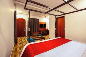 A hotel room with a bed, wooden flooring, a desk, a chair, and a television. - Villa Elixir Fort Kochi (Kochi)