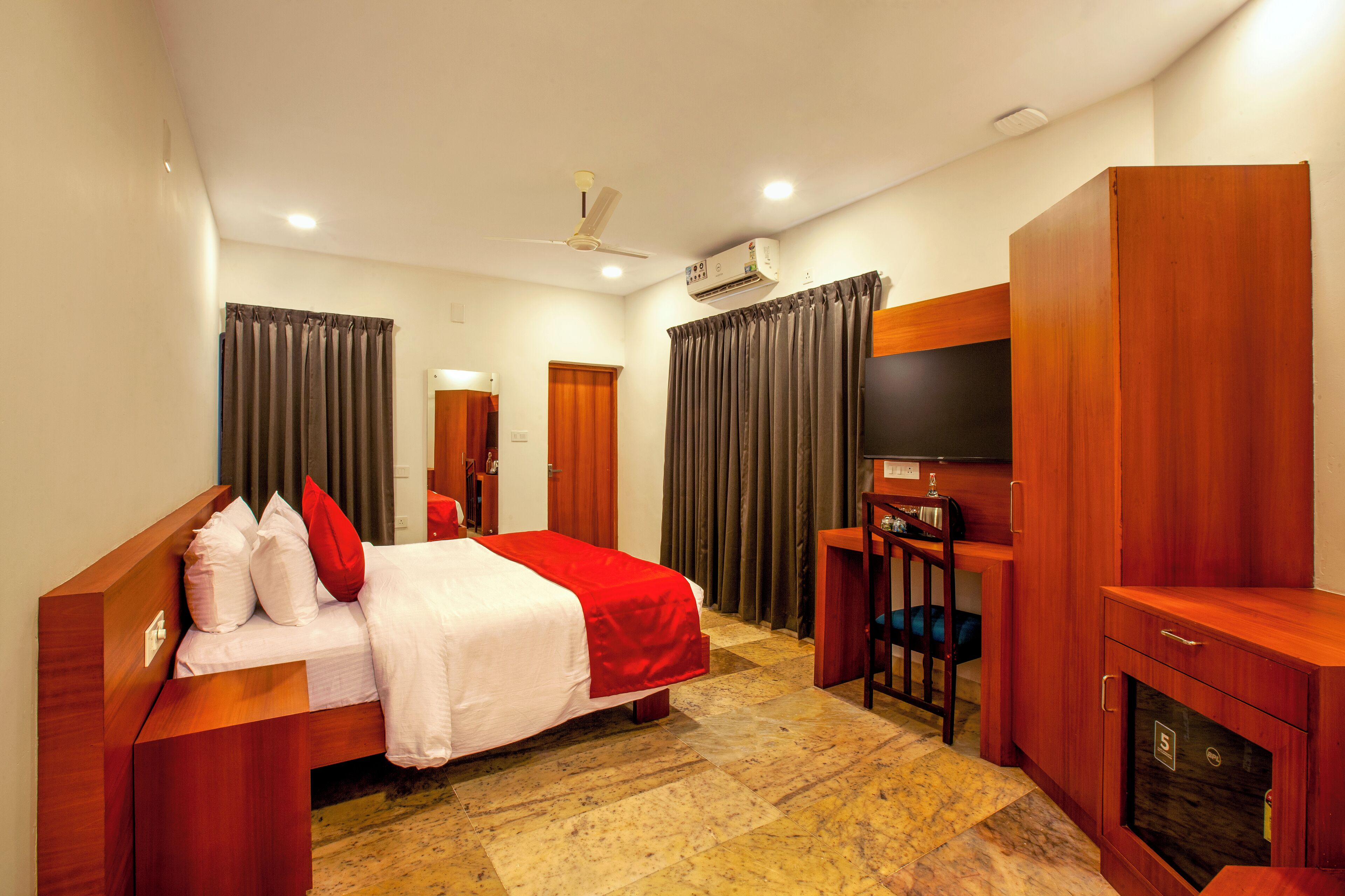 A hotel room with a bed, a desk, a TV, and a wardrobe.