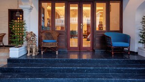 A hotel entrance with a grand staircase, a lion statue, and two wicker chairs. - Villa Elixir Fort Kochi (Kochi)