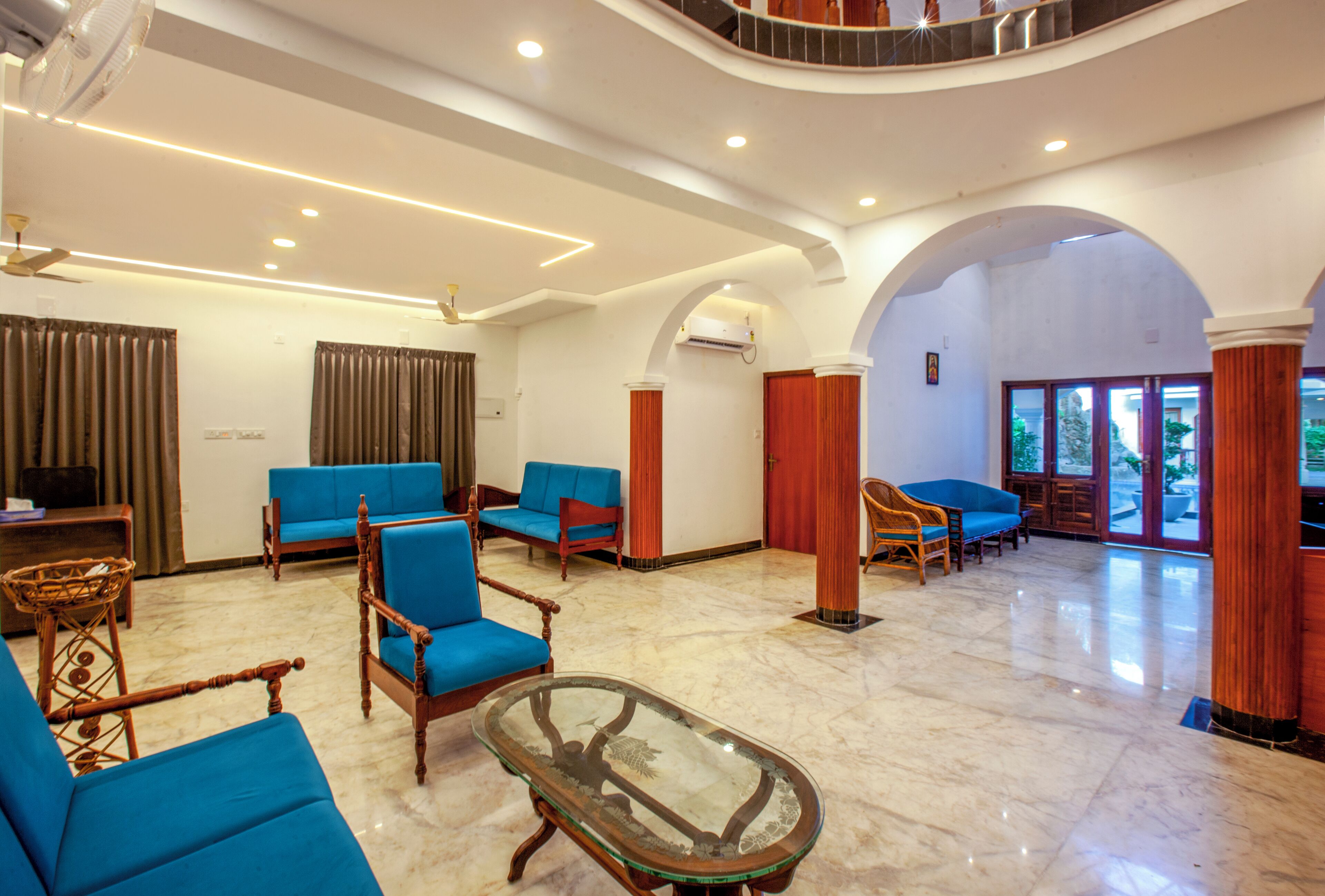 A spacious lobby with blue sofas, a glass coffee table, and a marble floor.