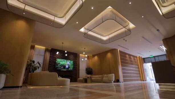 A modern lobby with a large flat-screen TV, comfortable seating, and a decorative ceiling design. - Wafa Residence (Riyadh)