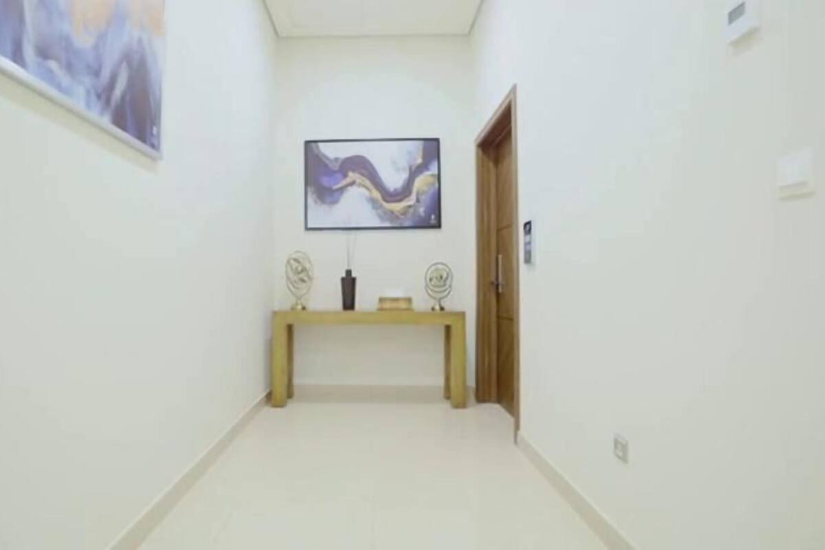A hallway with a wooden bench, a framed abstract painting, and a door.
