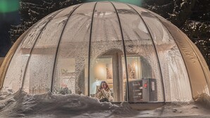 A snow-covered dome structure with a visible interior including a window and a heater. - Ice and light village (Luleå)