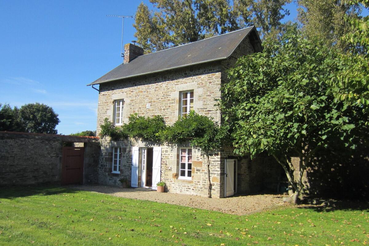 A stone house with a two-story structure, a front door, and a small garden area.