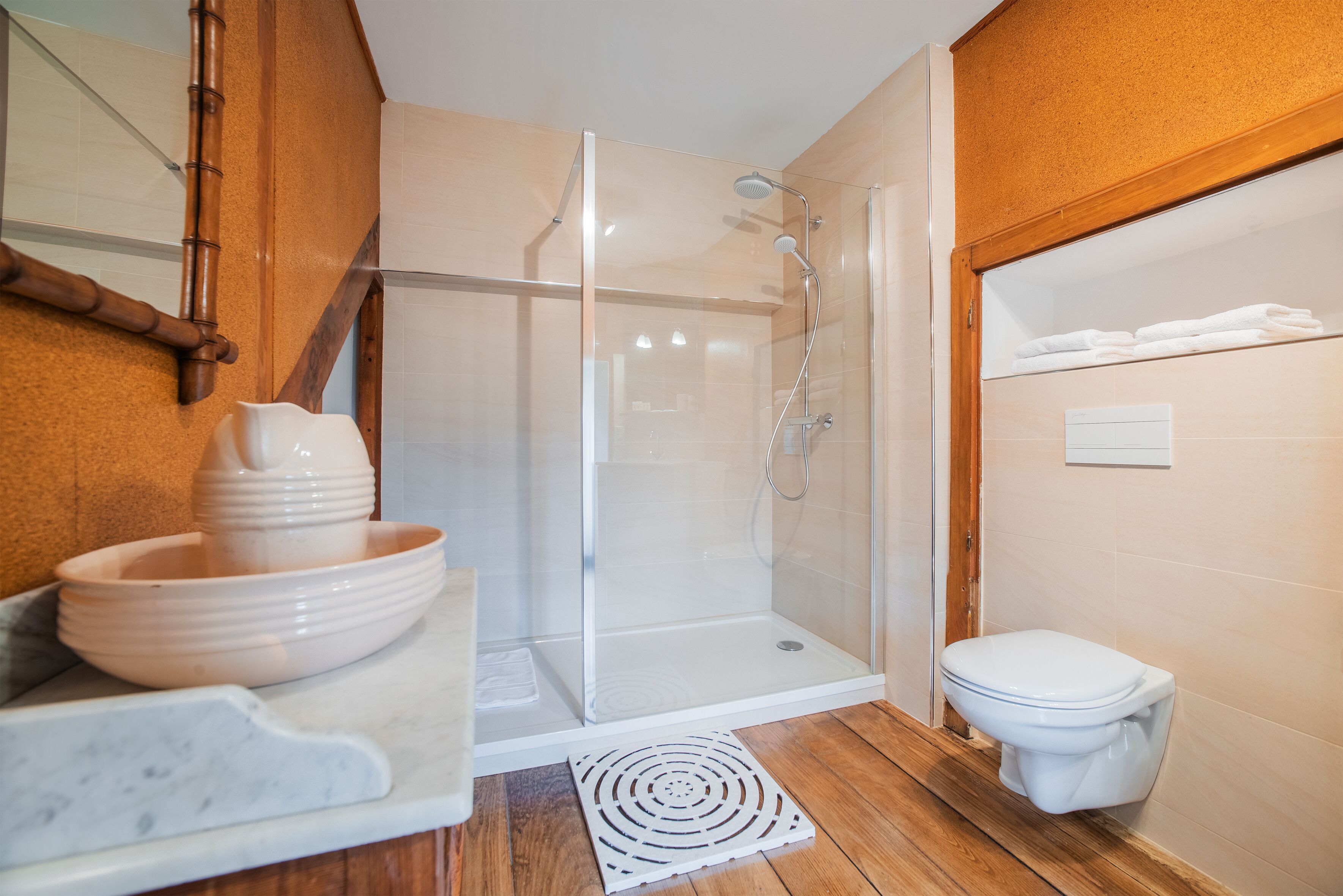A modern bathroom with a glass-enclosed shower, a white toilet, and a marble sink with a bowl.