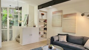 A modern living room with a grey sofa, a glass coffee table, and a bookshelf.