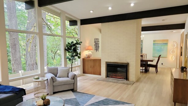 A spacious living room with a fireplace, large windows, and a modern design.