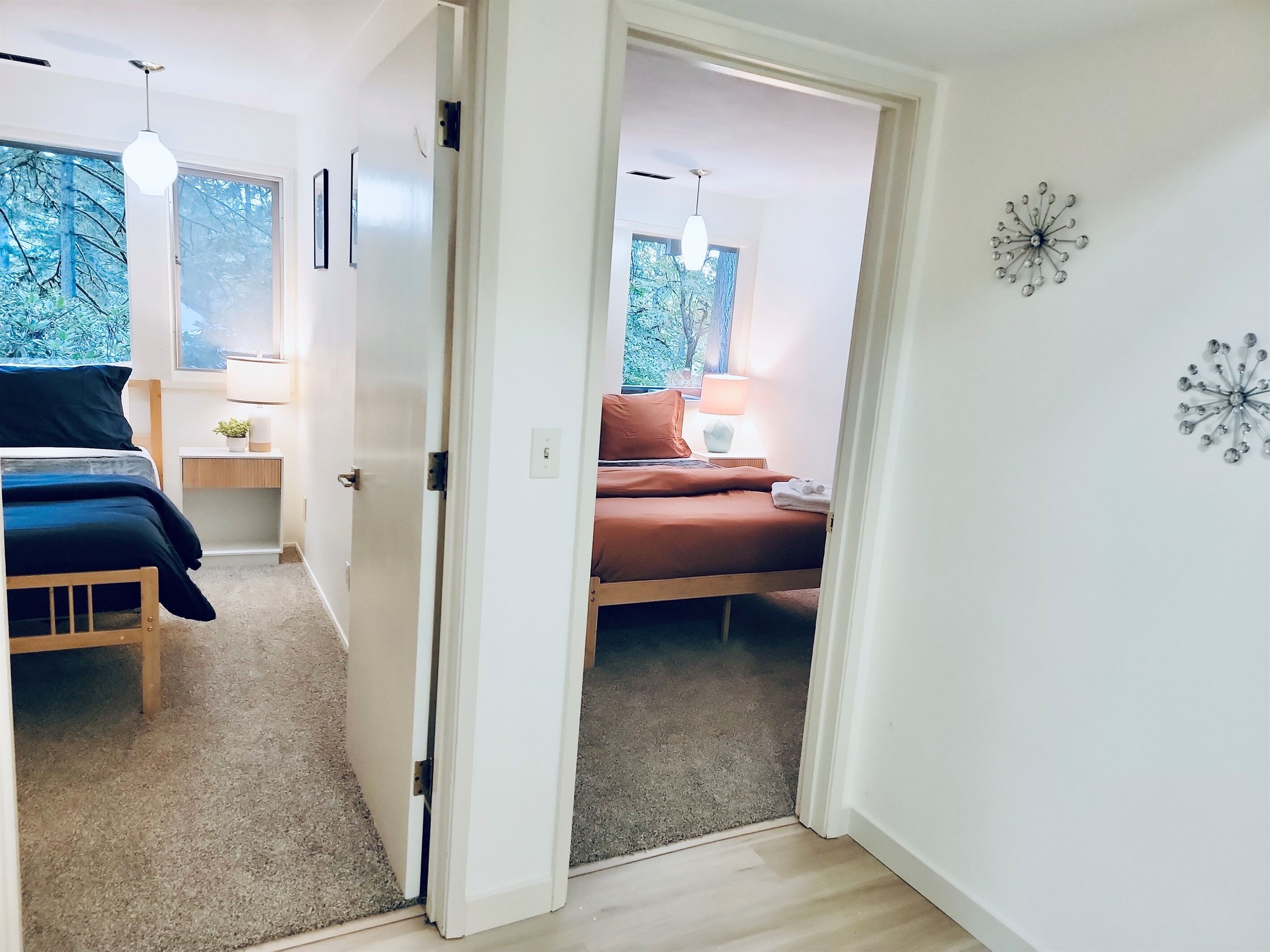 A modern bedroom with a bed, bedside table, and a view of greenery through the window.