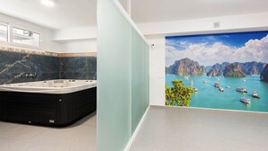 A bathroom with a large bathtub, a window, and a mural of a coastal scene. - Villa Selvetta - Luxury Villa next to Puerto Marina Benalmádena (Benalmádena)
