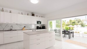 A modern kitchen with white cabinets, a marble backsplash, and a large island with drawers. - Villa Selvetta - Luxury Villa next to Puerto Marina Benalmádena (Benalmádena)