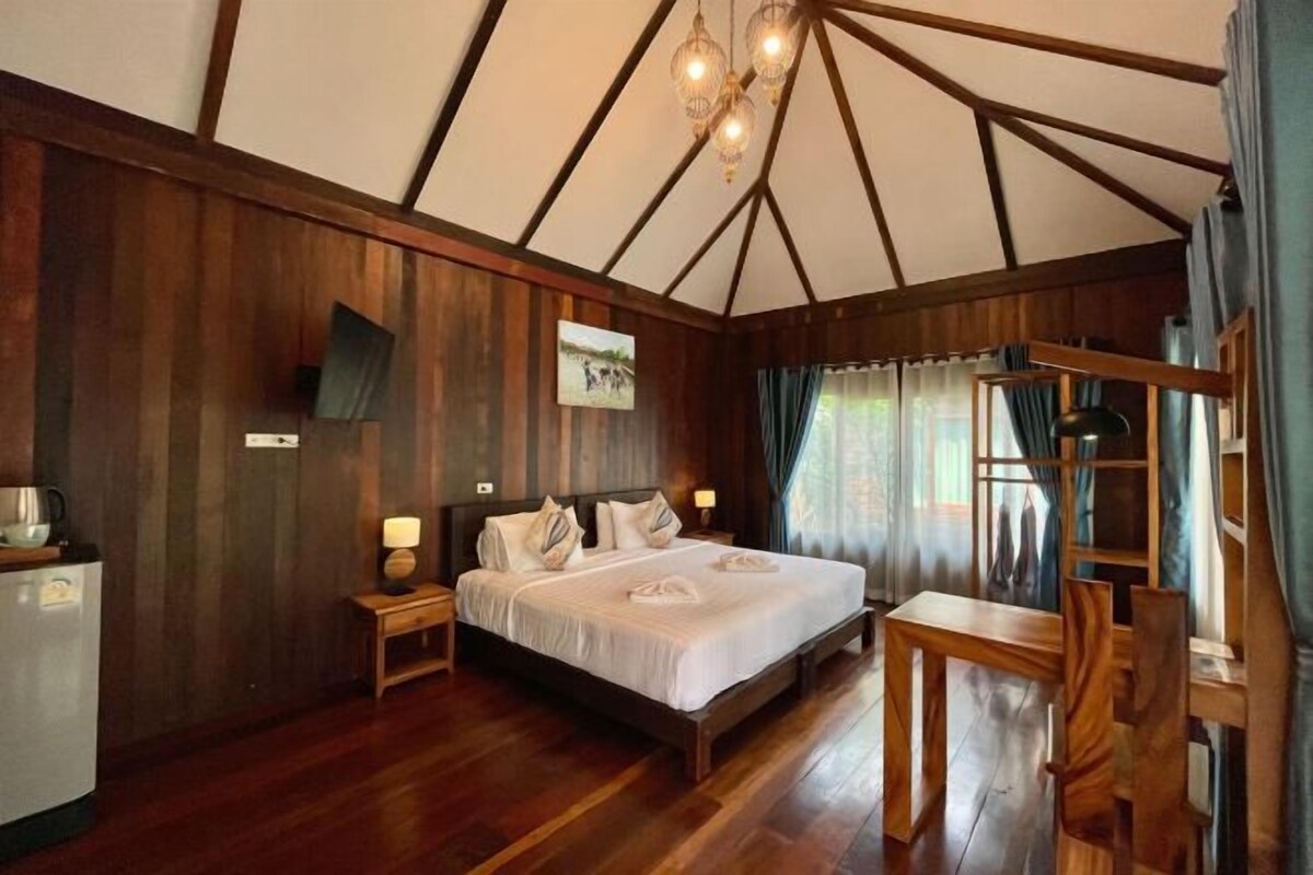 A room with a bed, bedside tables, a desk, and a chair.