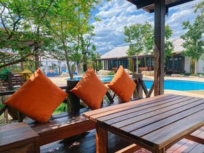 Eine Holzterrasse mit orangenen Kissen und einem Poolbereich.