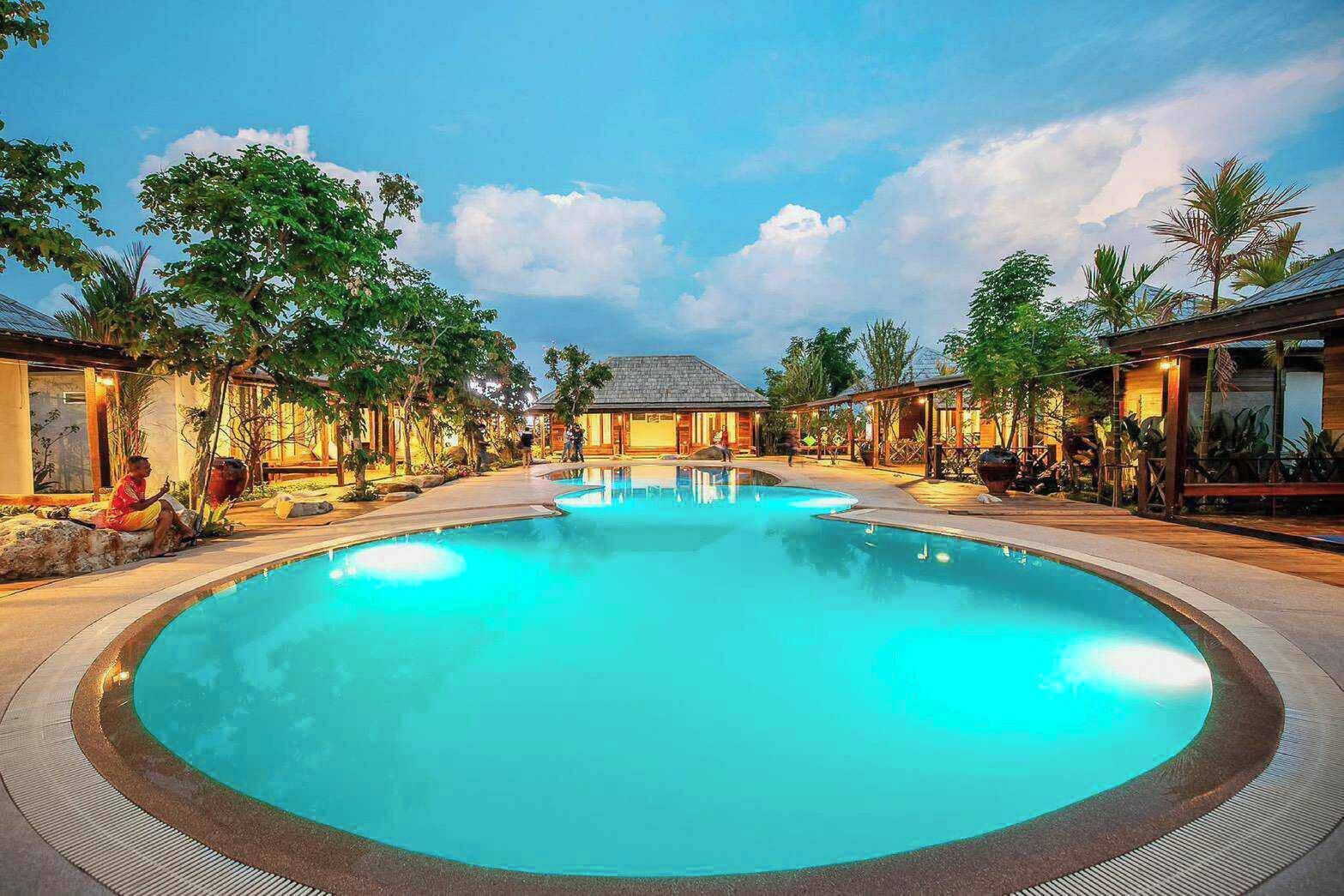 Una amplia piscina al aire libre rodeada de edificios en un entorno tropical.